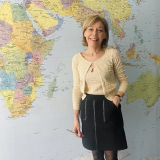 Insegnante di francese per studenti avanzati presso Ardevaz SLS si trova davanti alla mappa del mondo.