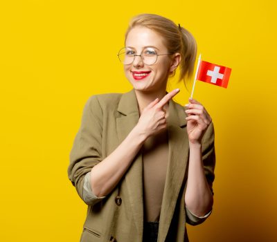 Счастливая студентка указывает на швейцарский флаг.